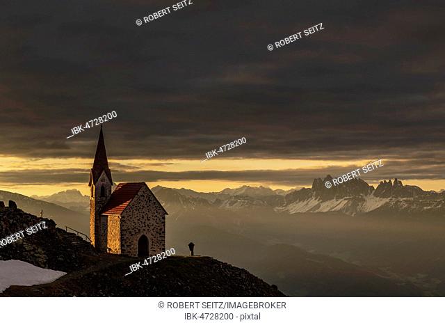 Latzfonser cross chapel at sunrise with dramatic clouds and South Tyrolean mountains, Sarntaler Alps, San Martino, Sarntal, South Tyrol, Italy