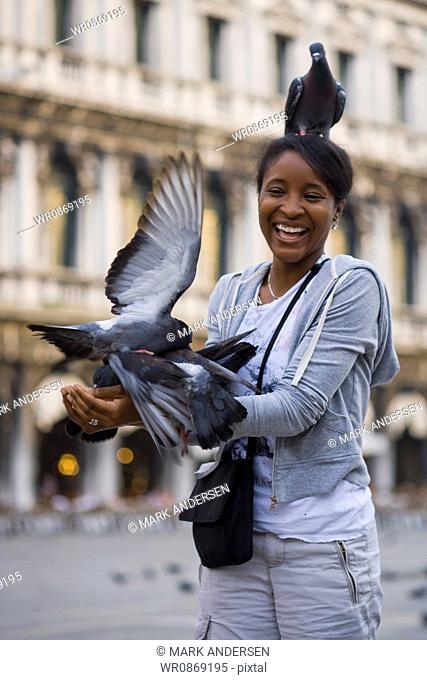 Woman in square with pigeon on head smiling