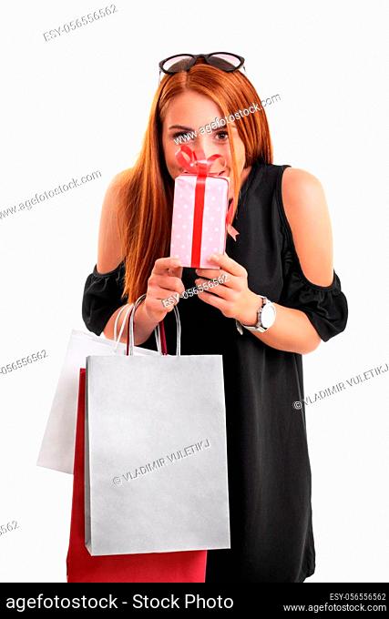 Beautiful young woman in a black dress holding shopping bags and present, isolated on a white background. Shopping concept. Gift concept