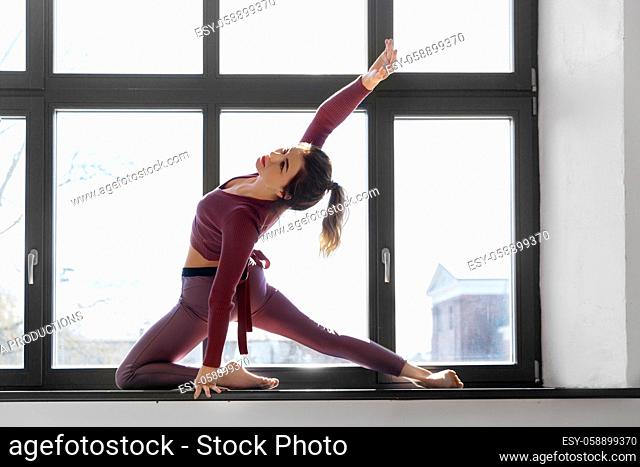 woman doing yoga exercise on window sill at studio