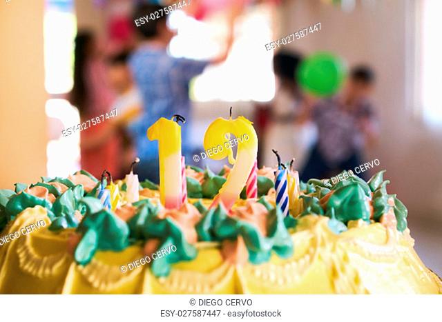 Group of happy children celebrating birthday at home, kids and friends having fun at party. Close-up of cake with candles