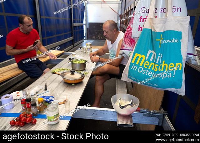 13 September 2023, Hesse, Gräfenhausen: Truck drivers prepare their lunch at a makeshift dining table on the loading area of a truck in the parking lot of the...