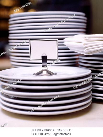 Stacks of Plain White Plates, White Linen Napkins and a Blank Place Card