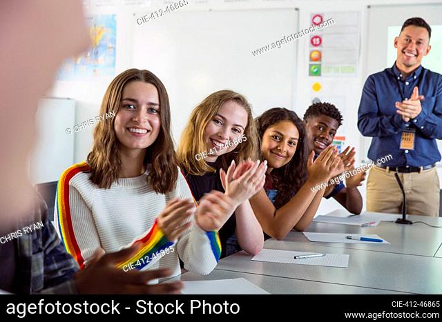 Happy high school students clapping in debate class