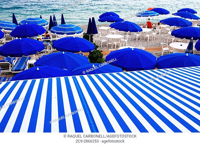 Beach loungers and parasols in 'Neptune Plage' stone beach. Nice, French Riviera, France