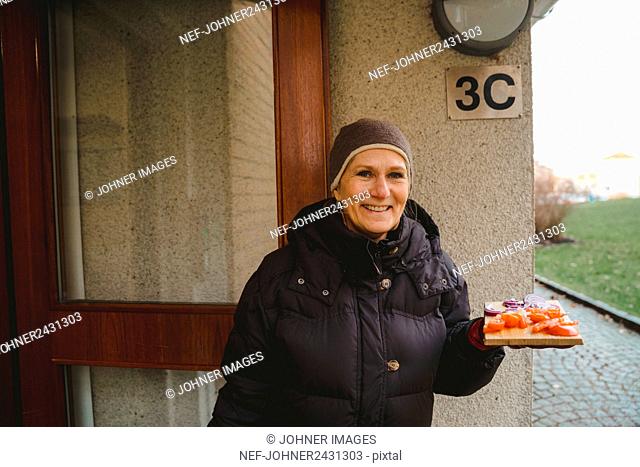 Smiling woman holding food on chopping board