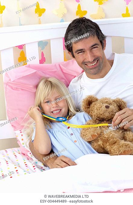 Daughter and father playing with a stethoscope and a teddy bear