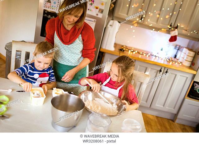 Mother and kids preparing dough for Christmas cookies