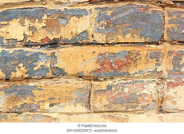 Old brick wall with remnants of yellow and red paint