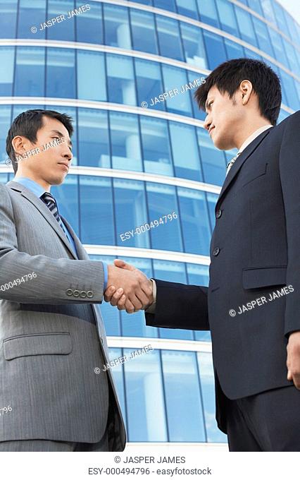 Businessmen Shaking Hands outside office building low angle view