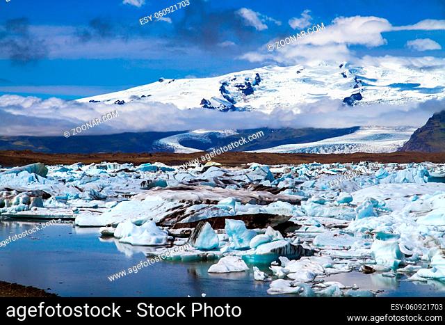 Clear and cold day in July. Arctic Circle. White and blue icebergs and ice floes reflected in the water. Iceland. The lagoon Jokulsaurloun
