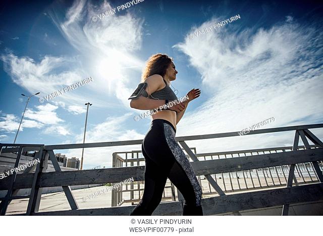 Young athletic woman running on a pier