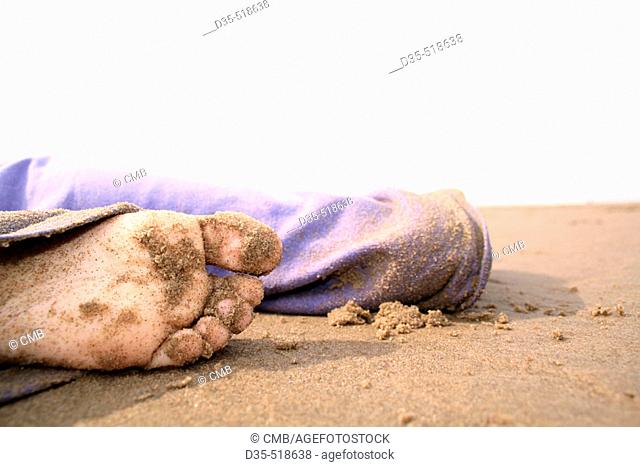 Young girl in blue sandy slack laying on beach