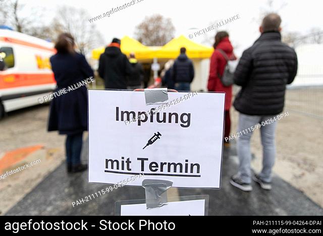 15 November 2021, North Rhine-Westphalia, Bielefeld: People with an appointment for a vaccination stand in a queue in front of a vaccination tent