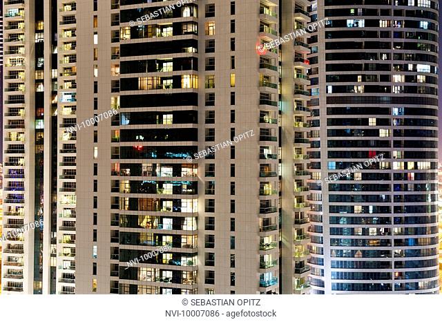 Illuminated facades of high-rise buildings in Jumeirah Lakes Towers JLT at night, New Dubai, UAE