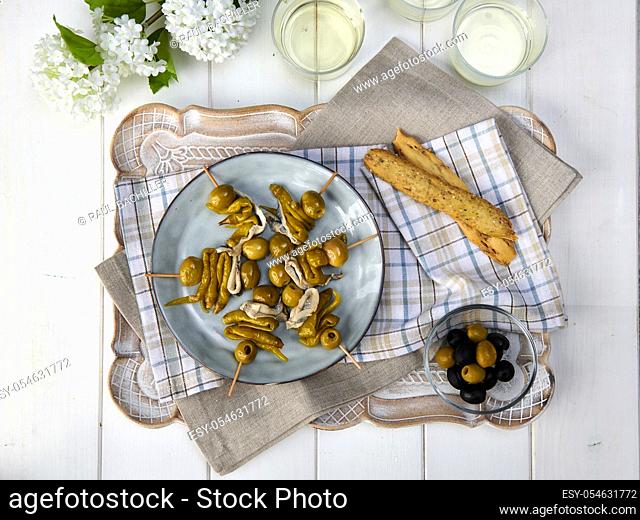 olive and anchovy flag with glass of wine in white background