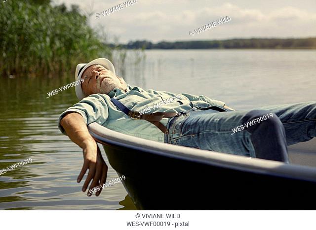 Senior man relaxing in rowing boat on a lake
