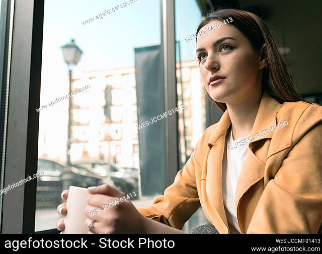 Beautiful woman sitting by glass window at coffee shop