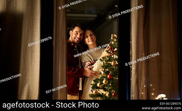 happy couple decorating christmas tree at home
