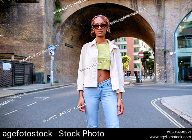 Young woman wearing sunglasses standing on footpath