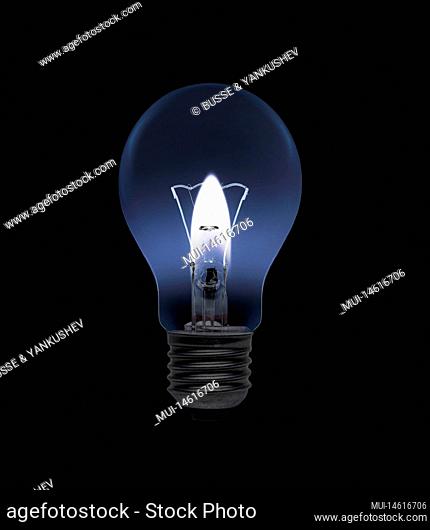 Incandescent lamp with a candle as a power source against black background