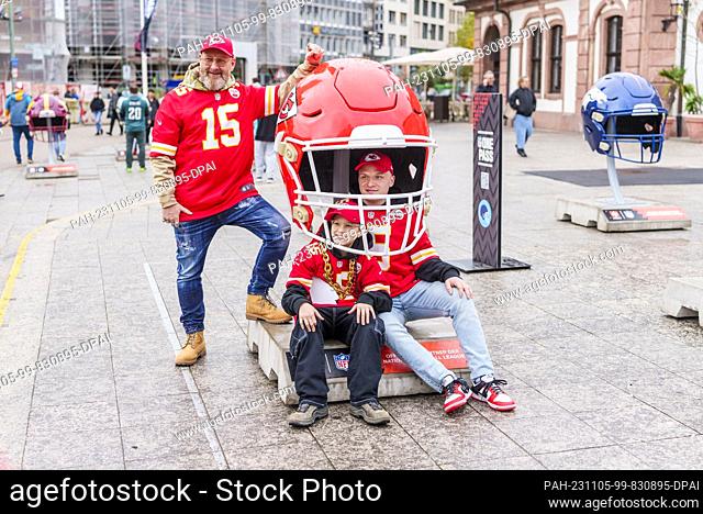 05 November 2023, Hesse, Frankfurt/Main: Father Oliver (l-r) and his two sons Jan and Noah have their photo taken with an oversized Kansas City Chiefs helmet in...