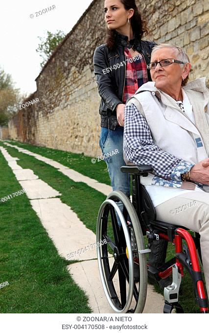 Young woman pushing an elderly lady in a wheelchair
