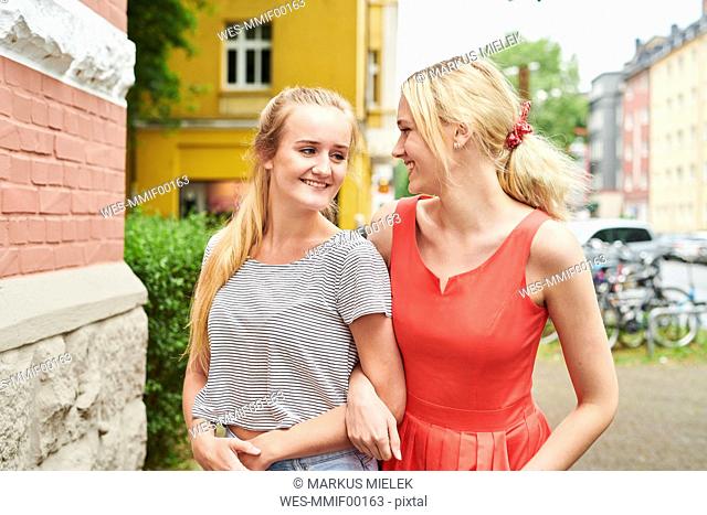 Two happy young women arm in arm in the city