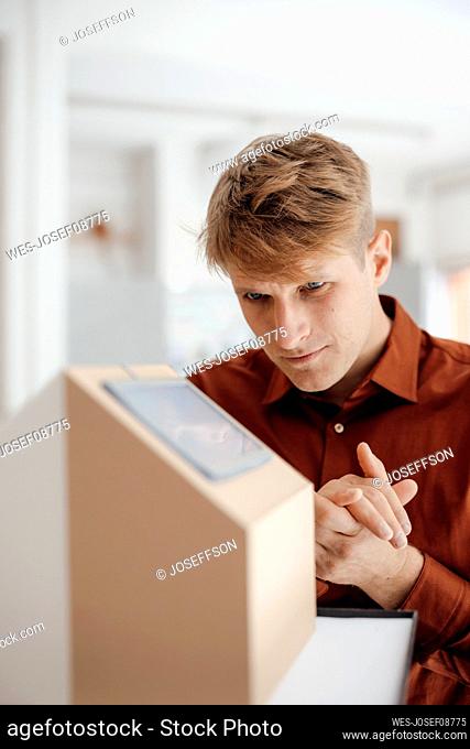Businessman with hands clasped looking at house model in office