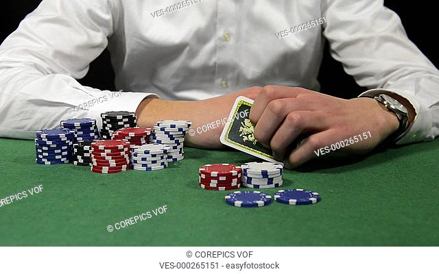 Poker player with a stack of chips showing his hand with a pair of kings, sitting back and folding his arms