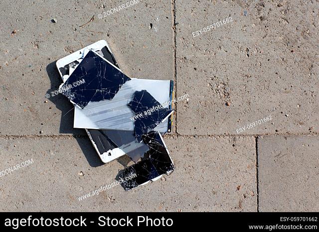 Broken screen mobile phone lies on ground