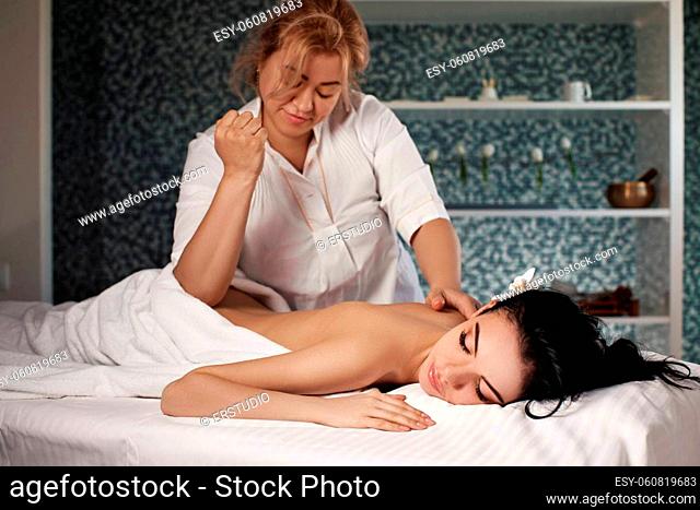 Relaxed beautiful young woman receiving massage in spa salon. Beauty treatment