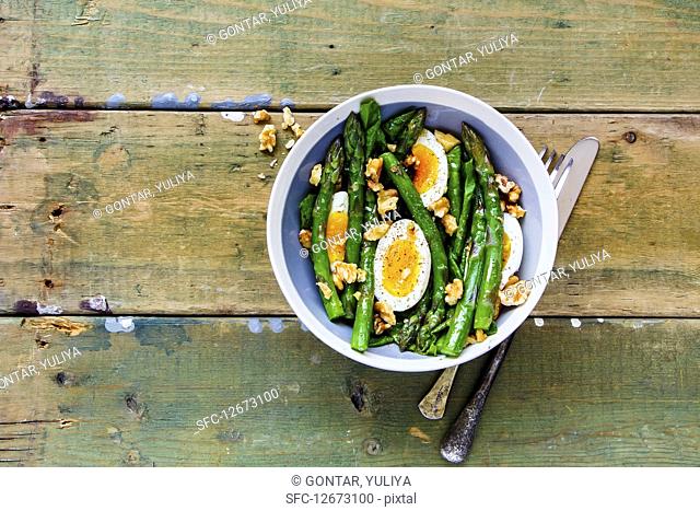 Aspargus and eggs salad in bowl with on rustic background