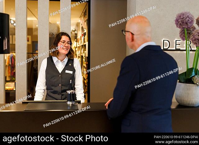08 June 2022, Baden-Wuerttemberg, Donaueschingen: ILLUSTRATION - A receptionist stands at the front desk of the Hotel ""Öschberghof"" and talks to a guest