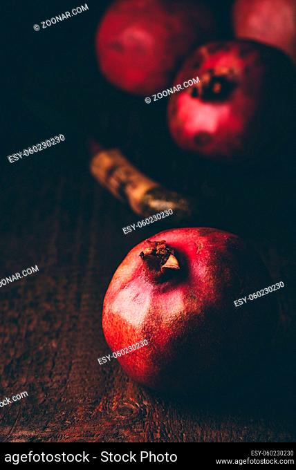 Pomegranate on wooden table. Knife and some fruits on background