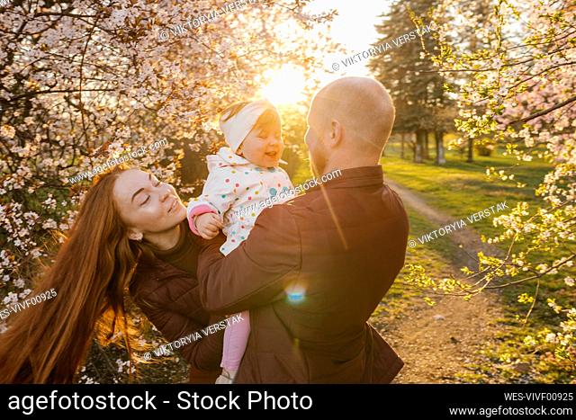 Family playing with daughter in park at sunny day