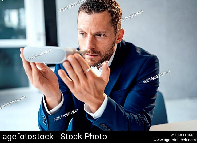 Businessman examining virtual reality headset in office