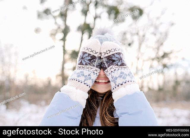 Happy girl wearing mittens covering eyes