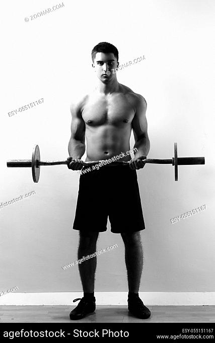 Young and muscular guy working out with barbell