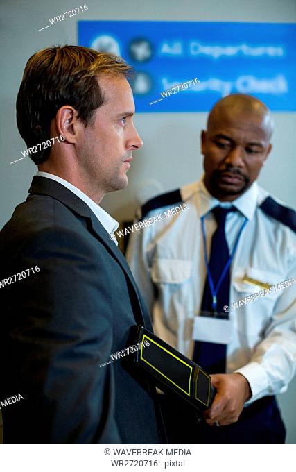 Airport security officer using a hand held metal detector to check a commuter