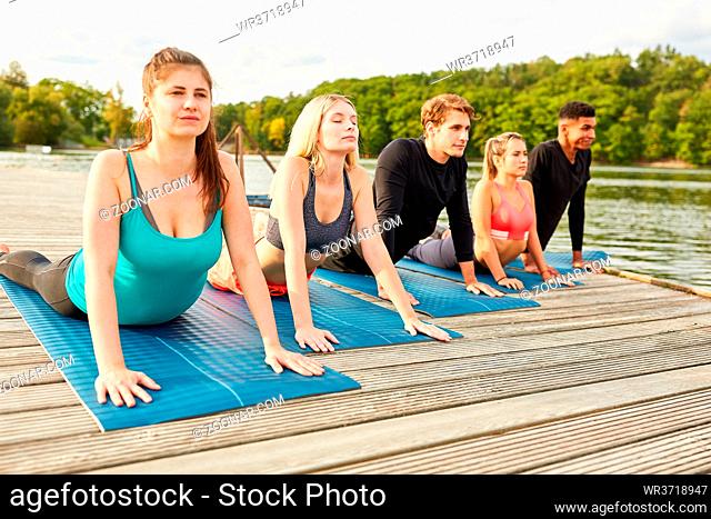 Gruppe junger Leute macht eine Dehnungsübung beim Sonnengruß im Yoga Kurs