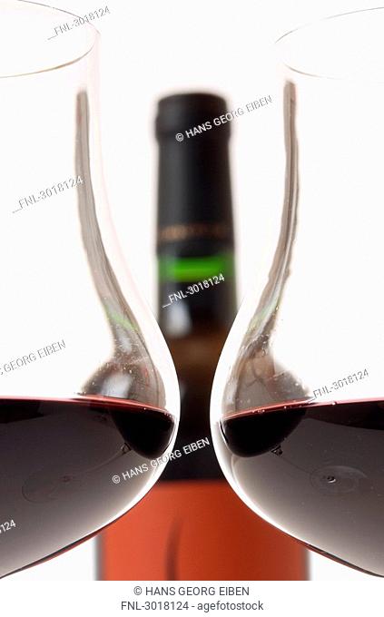 Two filled claret glasses in front of wine bottle, cross-section