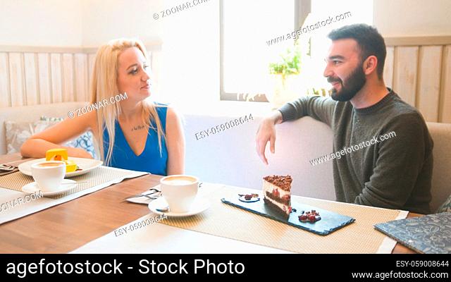 Young man and blonde woman takes the cups of coffee at the cafe, close up