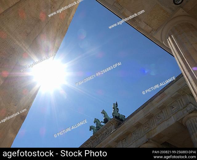 21 August 2020, Berlin: Between columns the Quadriga on the Brandenburg Gate can be seen against a blue sky on a day with high temperatures