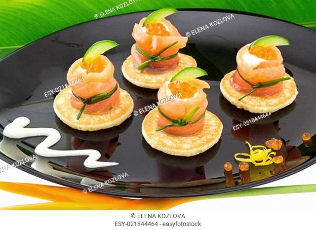 Red salmon roll with cheese, caviar and cucumber on” blinis”