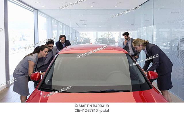 Customers looking at new car in car dealership showroom