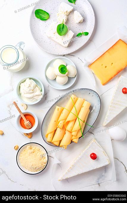 Fresh dairy products on white marble background. Assortment of cheese, honey, milk, yogurt. Top view