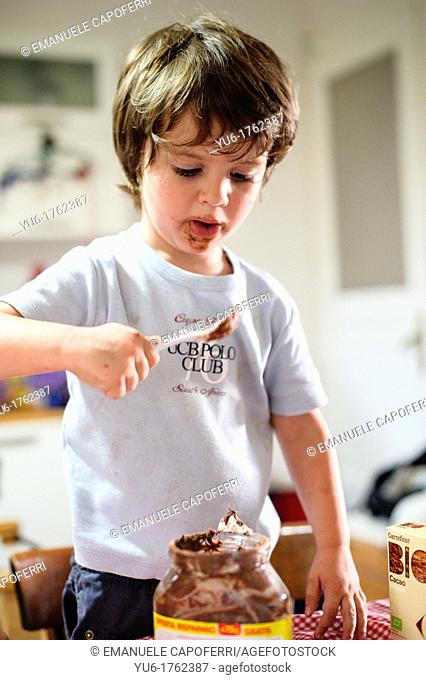 Child takes chocolate from the pot