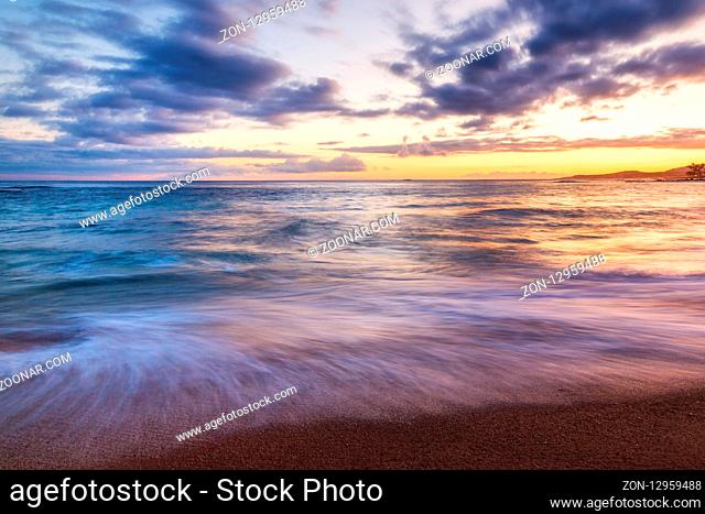 Sunset at a rocky beach with vivid warm colors and beautiful skies