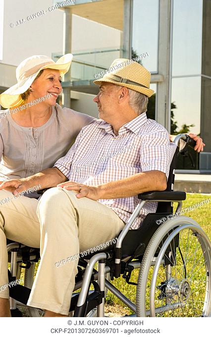 Retirement disabled man with wife sitting outdoors